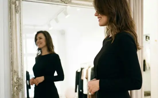 سيدة سعيدة تنظر للمرآة بعد عملية تكبير الثدي في تركيا بمستشفى ميديكال بارك لاستعادة الثقة والأنوثة.